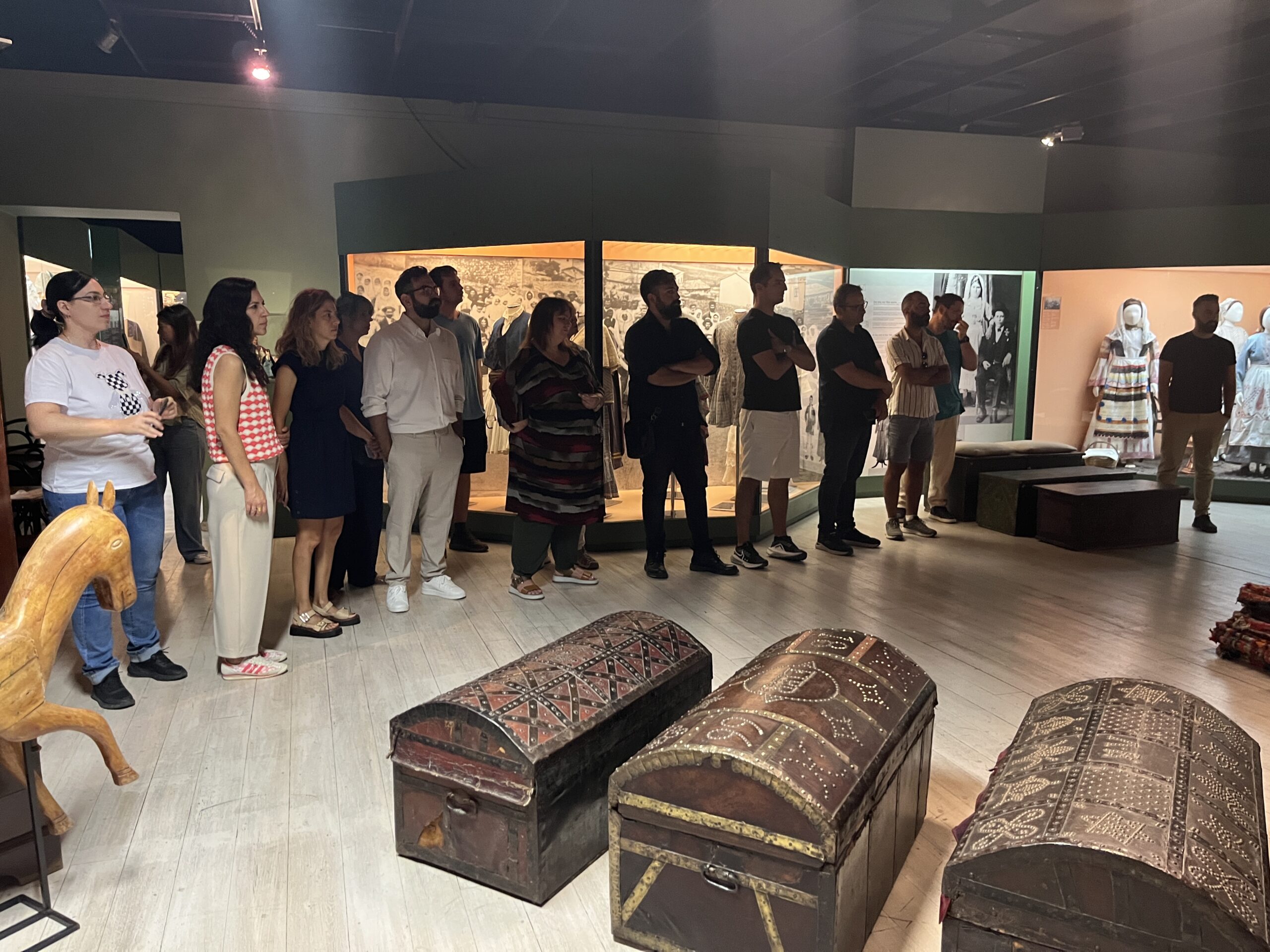 A group of about 20 people during a museum visit listening attentively.