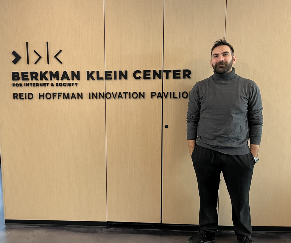 Person standing in front of a wall sign that reads “Berkman Klein Center for Internet & Society – Reid Hoffman Innovation Pavilion” in a modern office hallway.