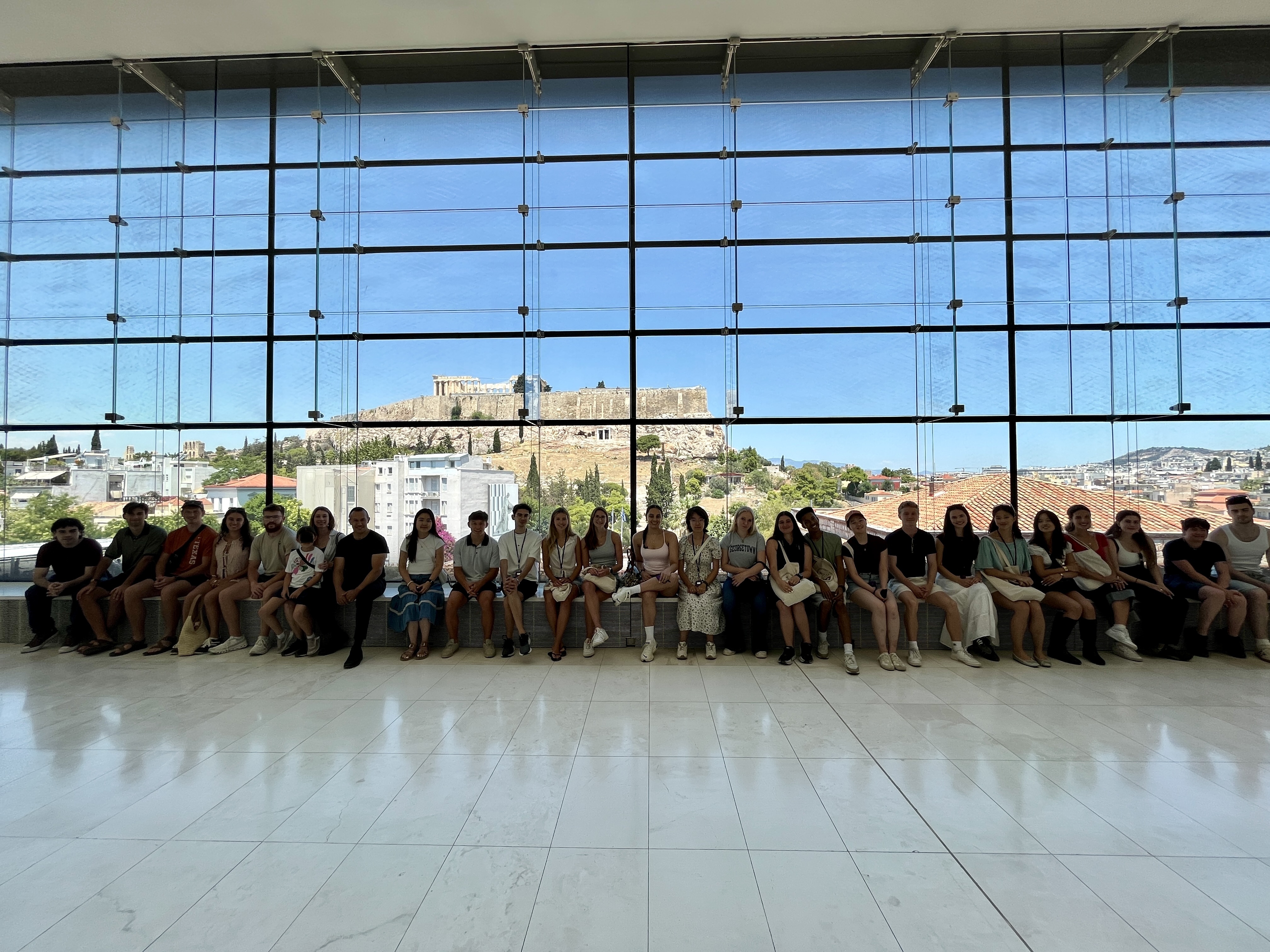 Participants from CHS Greece programs gathered at the Acropolis Museum in Athens with the Acropolis visible in the background.