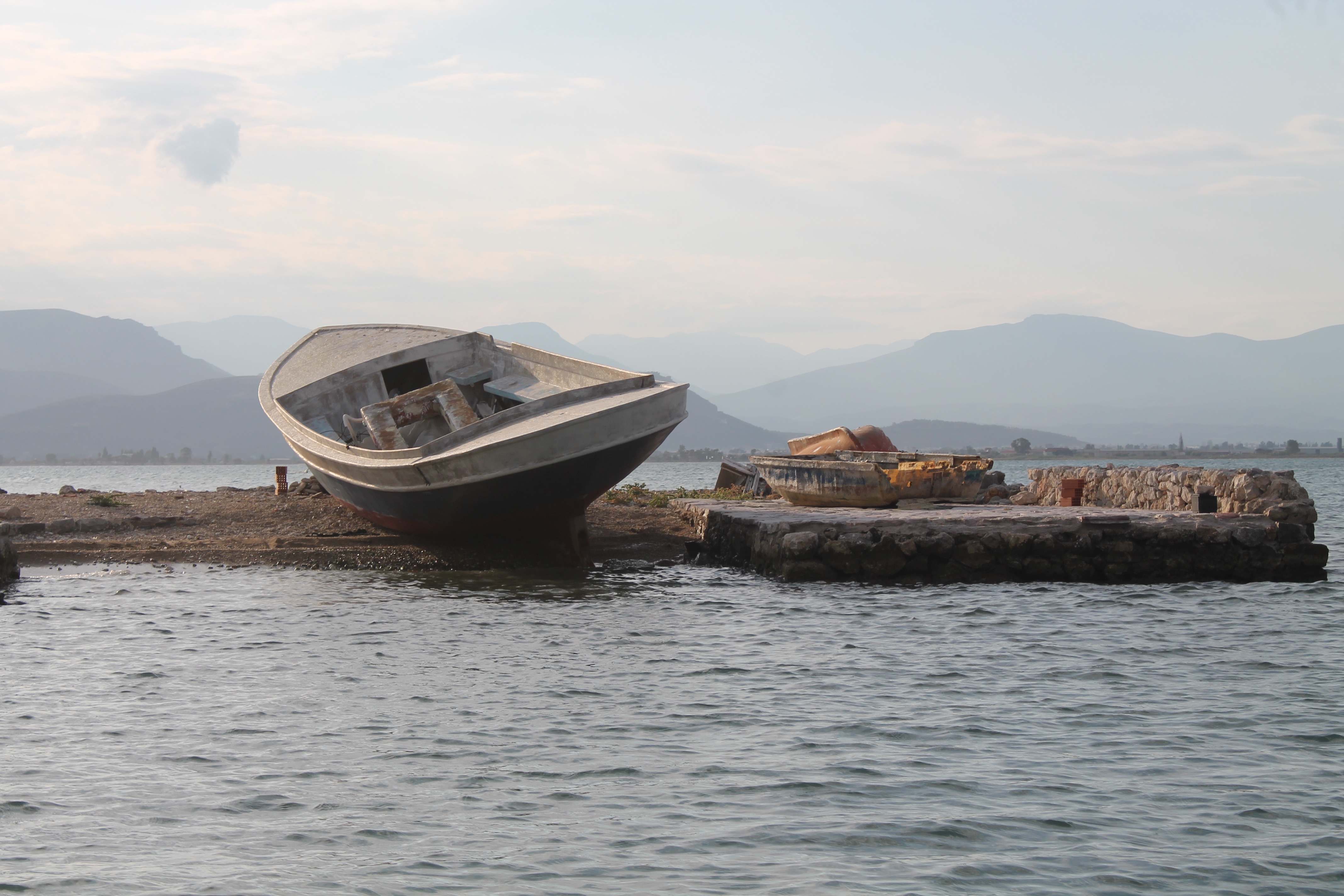 Small boat left ashore in a background full of the blue of the sea and the sky.
