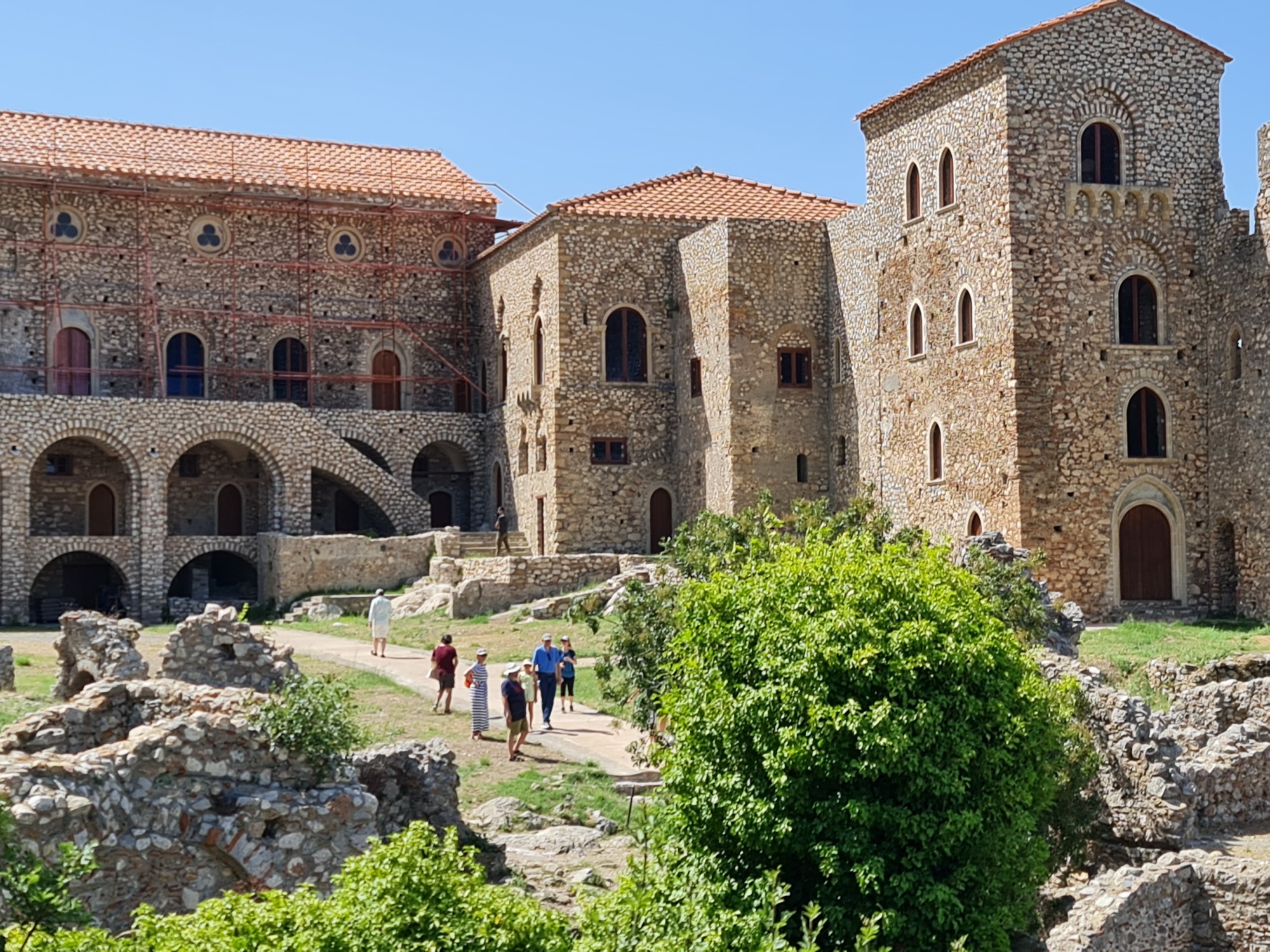 A small group of people walking towards a tall medieval palace on a sunny day.