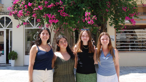 Four young people pose beneath a blooming bougainvillea tree in Nafplio.