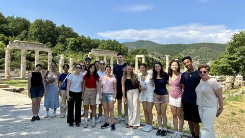 Group standing among ancient stone columns at an archaeological site. 