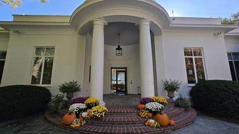 Front entrance of the CHS Washington, DC building, featuring white columns, brick steps, and seasonal displays of pumpkins and colorful chrysanthemums.