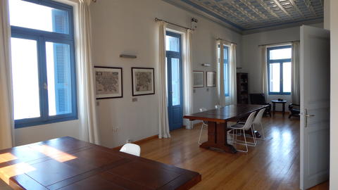 A room with two sturdy desks, wooden floor and wooden patterned ceiling.