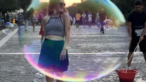 Young woman walking photographed through a soap bubble