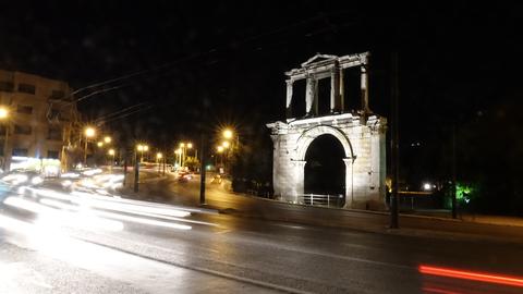 Night-view of the Arch of Hadrian in Athens in the background of a busy street with car lights.