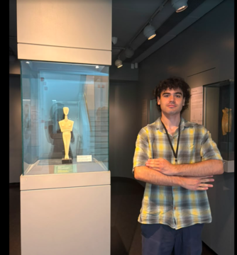 Lorenzo Levy stands beside a display case featuring a Cycladic figurine in the permanent collection galleries of the Museum of Cycladic Art.