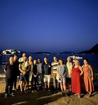 The workshop group photographed on the beach at dusk, with the gulf behind them.