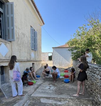 Workshop participants seated outdoors in a courtyard, washing and sorting archaeological finds.