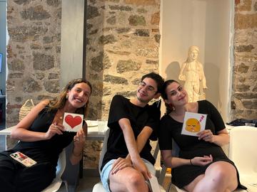 Three participants seated indoors during a group activity, holding illustrated cards.