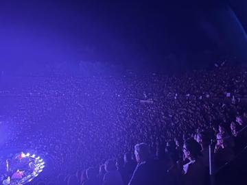 An open-air performance attended by a capacity crowd in the late evening.