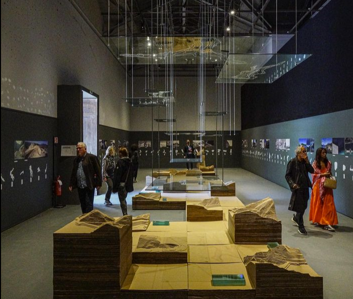 An exhibition space with people walking around and looking at the exhibits.