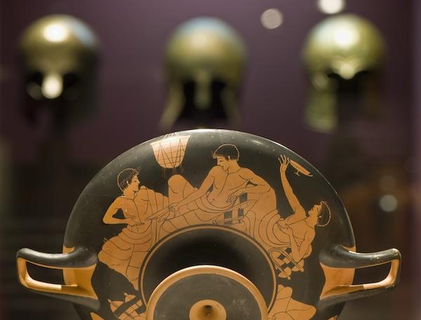 A close-up of an ancient ceramic piece depicting a scene of a symposium.
