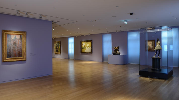 One of the Basil & Elise Foundation's rooms with multiple paintings on purple walls, around the famous sculpture of Edgar Degas 