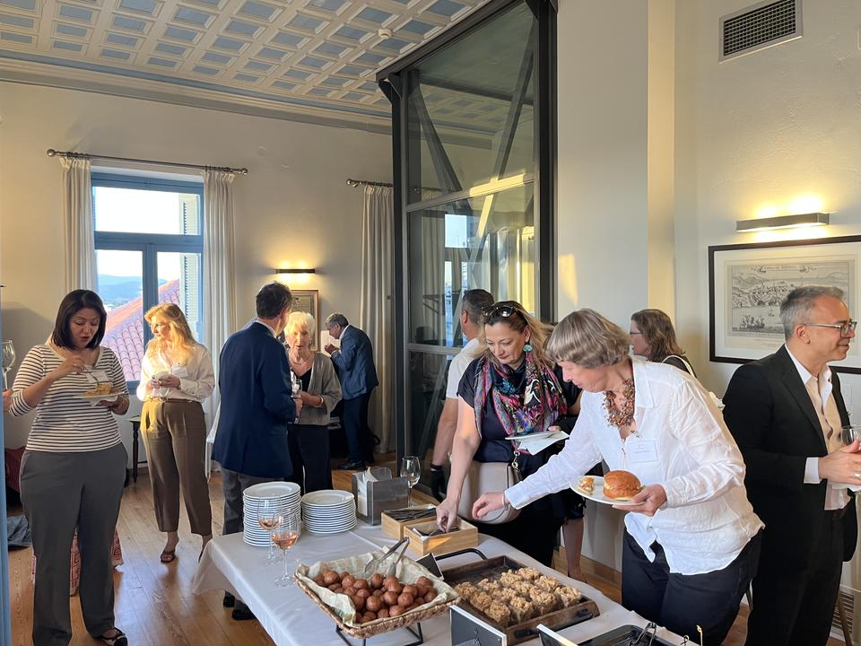 Attendees enjoying food and conversation around a buffet table during a conference reception.