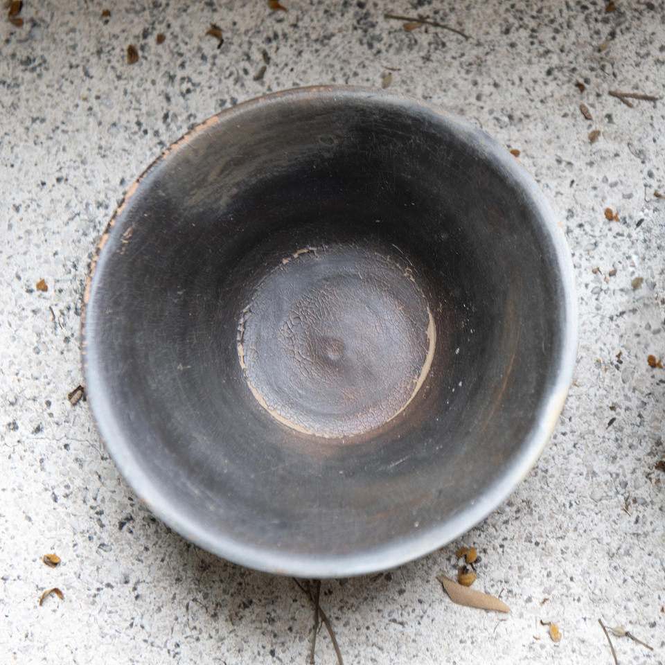 Top view of a round, dark ceramic bowl on a textured stone background.