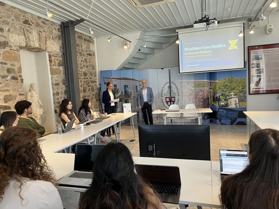 Students at CHS Greece during a lecture on bioethics case studies in genomic medicine, with two faculty standing at the front of the room.