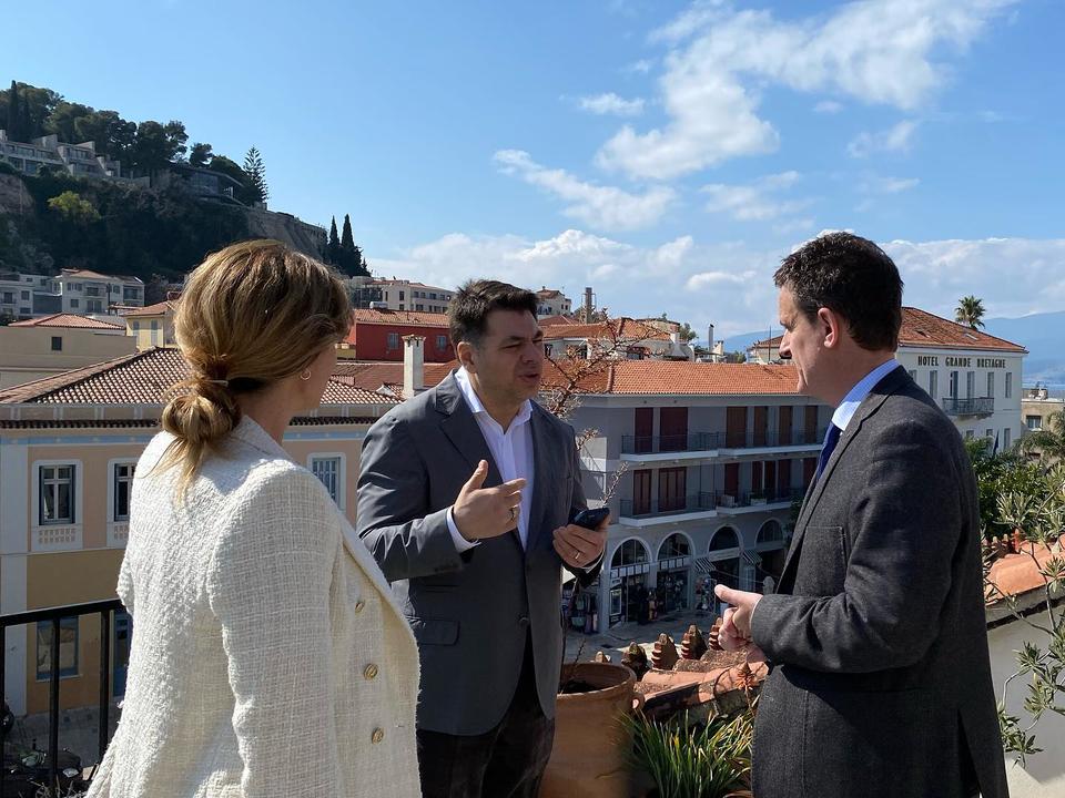 Two men and one woman standing on a terrace and engaging in conversation.